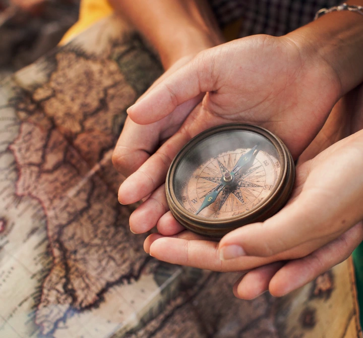  Mãos segurando uma bússola, simbolizando orientação e tecnologia para escolher o imóvel rural certo.